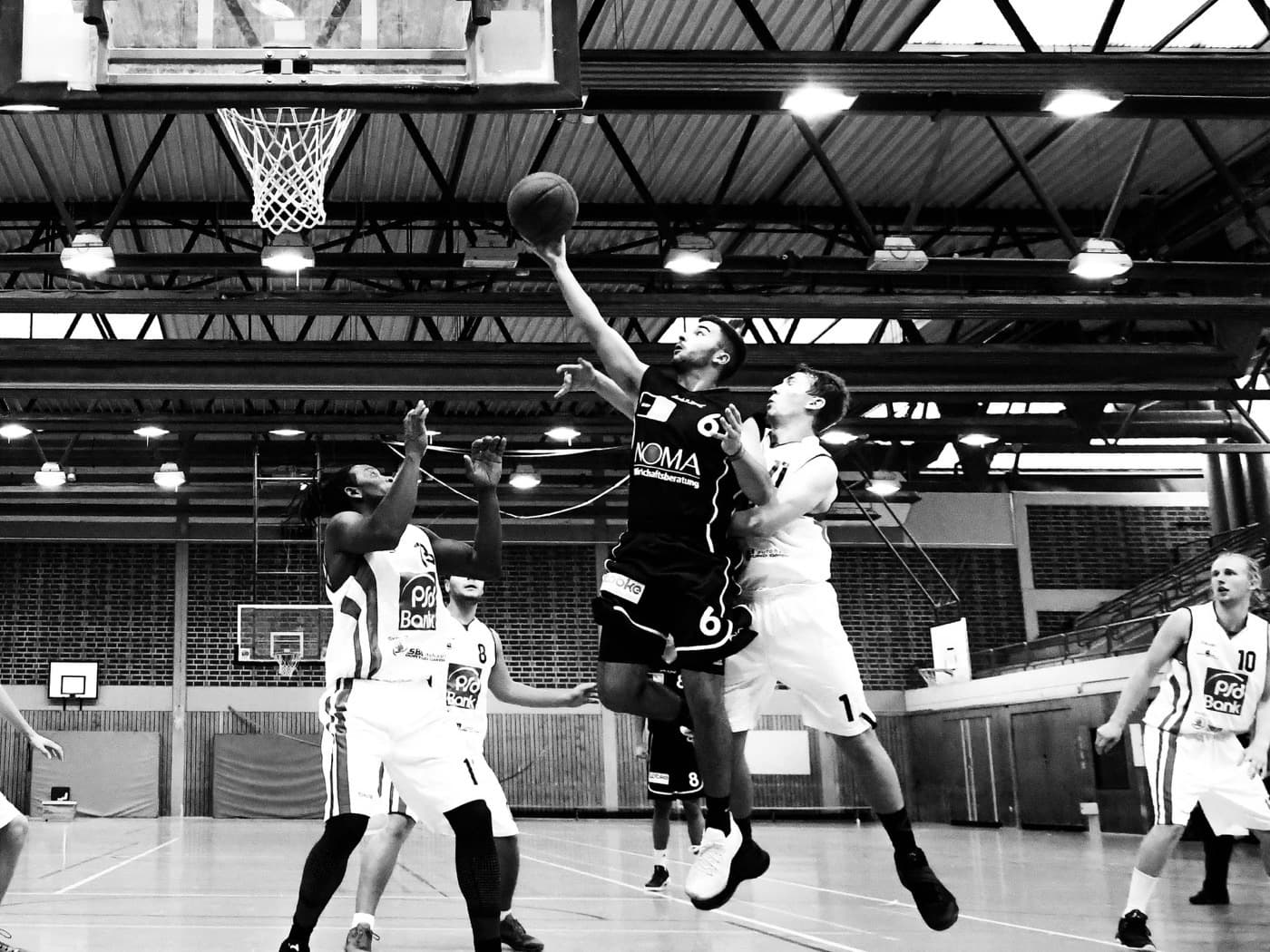 A guard rises for a layup under the basket